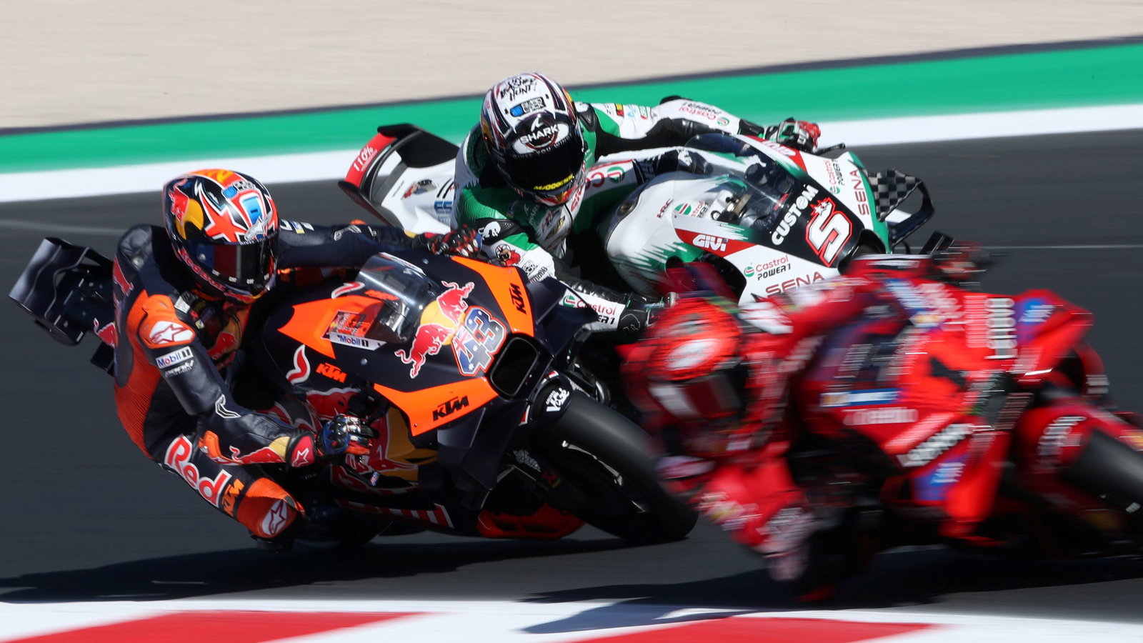 Jack Miller dives under Johann Zarco, chasing Francesco Bagnaia. 2024 San Marino MotoGP