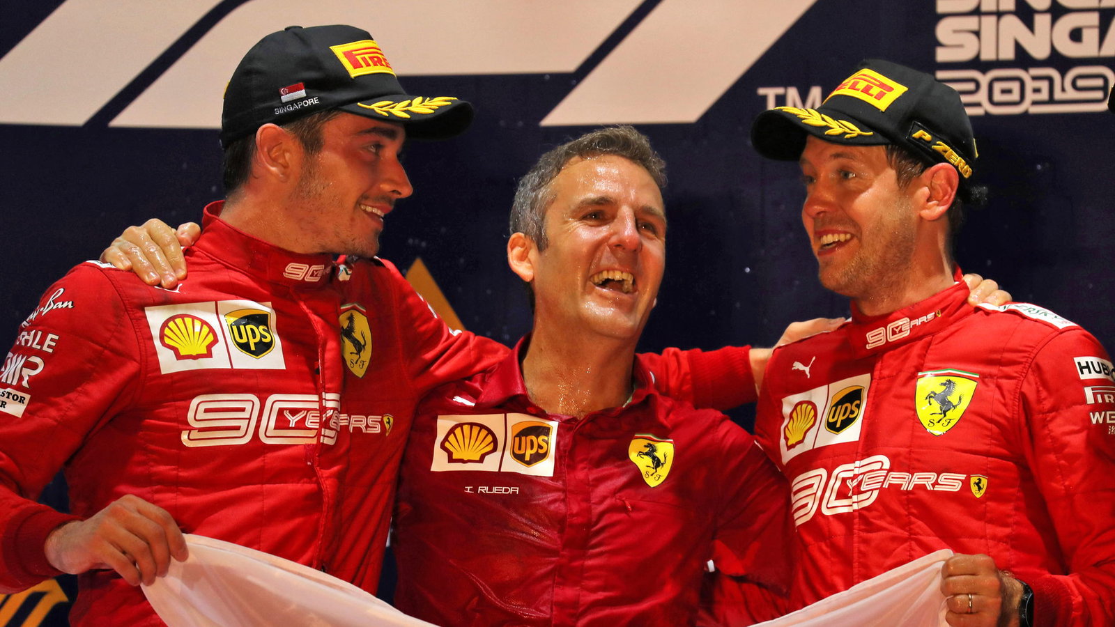Inaki Rueda stands between Charles Leclerc and Sebastian Vettel