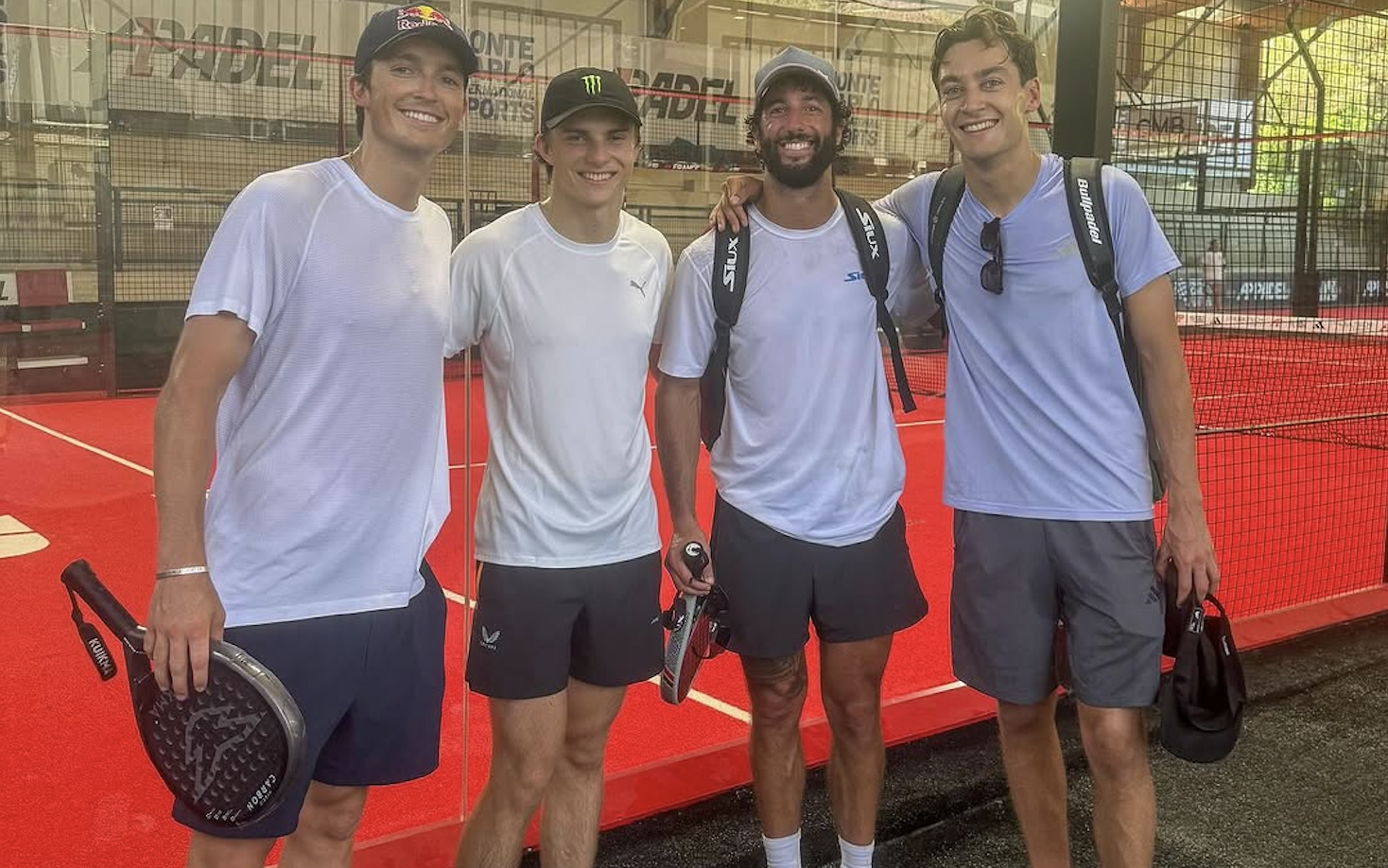 Daniel Ricciardo stands in between Oscar Piastri and George Russell