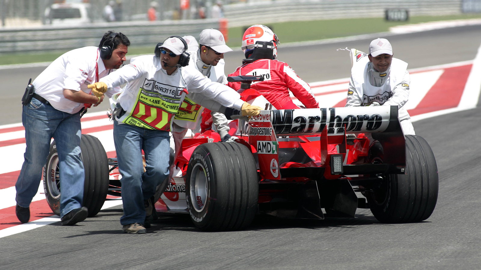 Marshals push Rubens Barrichello and the new Ferrari out of harms way