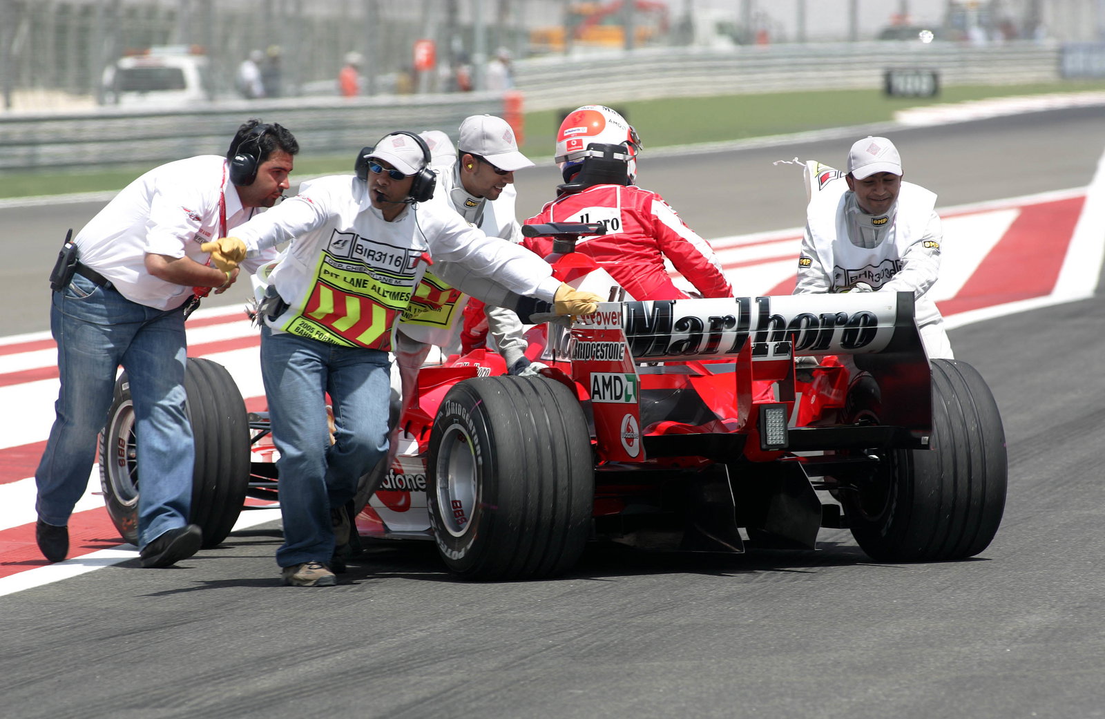 Marshals push Rubens Barrichello and the new Ferrari out of harms way