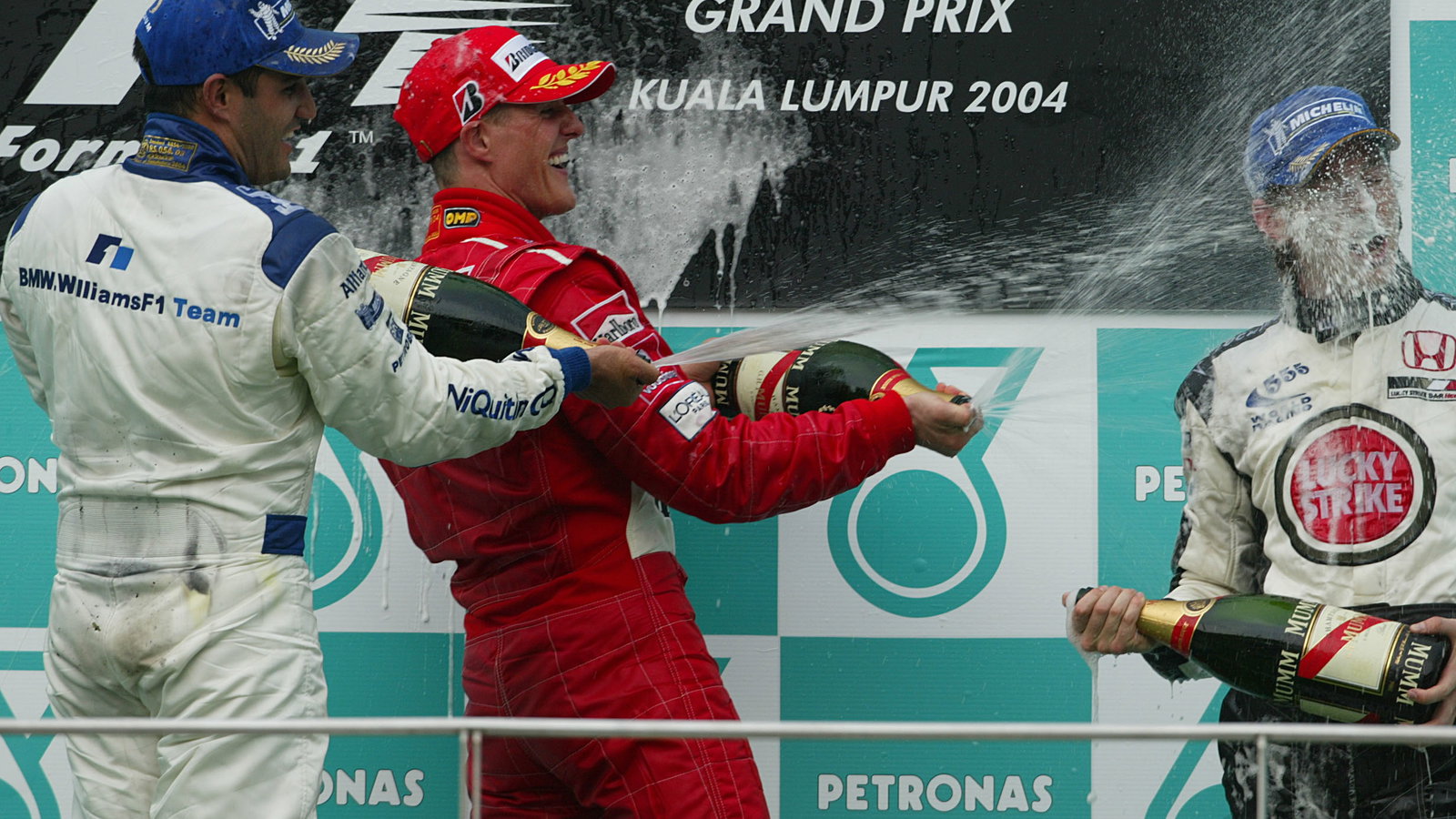 Malaysian GP winner Michael Schumacher [Ferrari] on the podium with Juan Montoya [2nd] and Jenson Bu