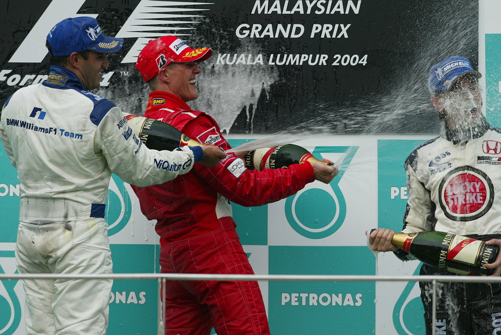 Malaysian GP winner Michael Schumacher [Ferrari] on the podium with Juan Montoya [2nd] and Jenson Bu