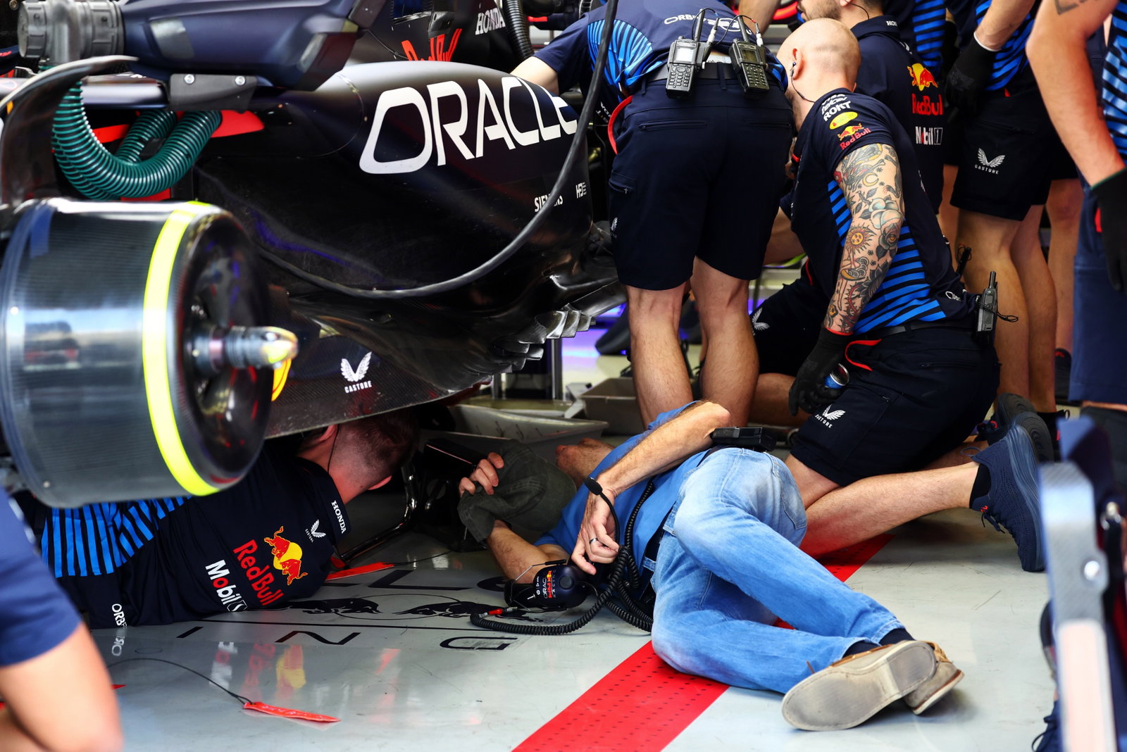 Adrian Newey (GBR) Red Bull Racing Chief Technical Officer looks under the Red Bull Racing RB20 of Sergio Perez (MEX) Red